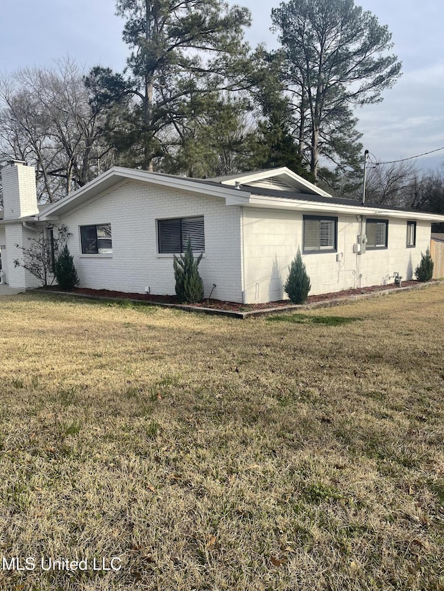 view of property exterior with concrete block siding, a lawn, and brick siding