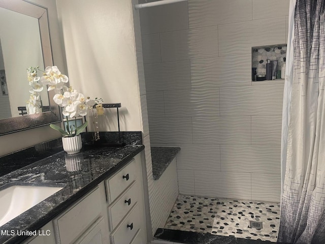 bathroom with tiled shower and vanity