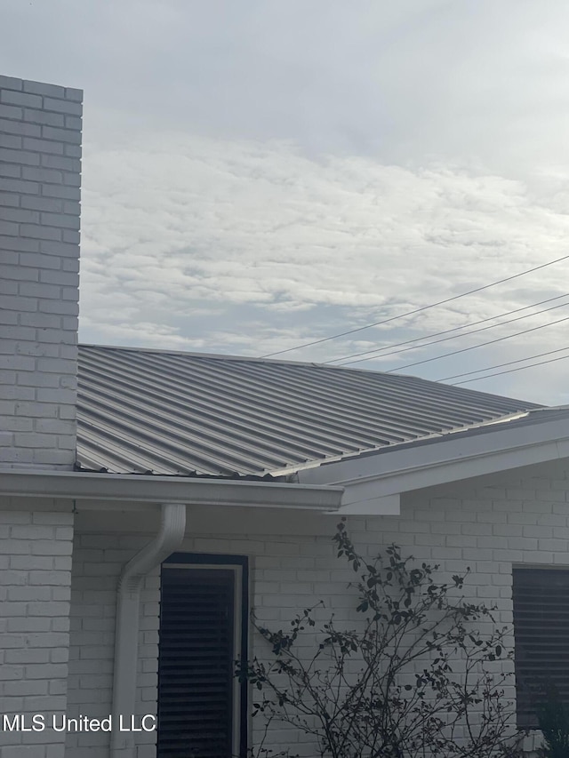 exterior details with a downspout, gutters, and metal roof