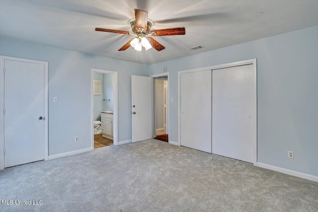 unfurnished bedroom with ceiling fan, a closet, ensuite bathroom, and light carpet