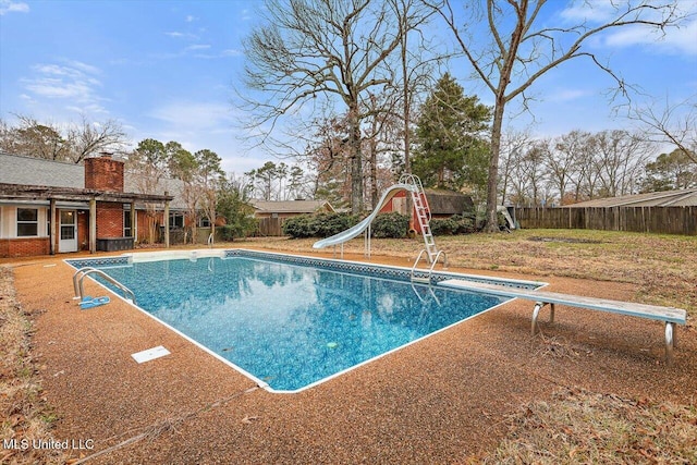 view of pool featuring a diving board and a water slide