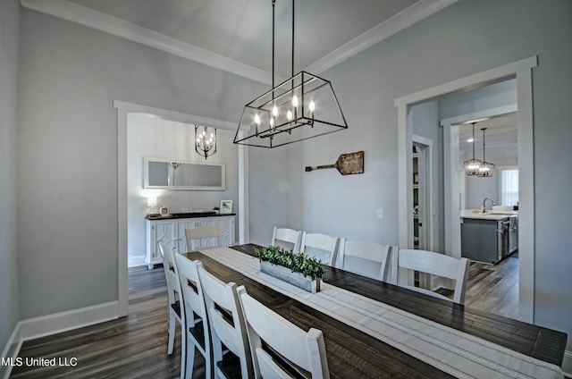 dining room with dark wood-type flooring, a notable chandelier, baseboards, and ornamental molding