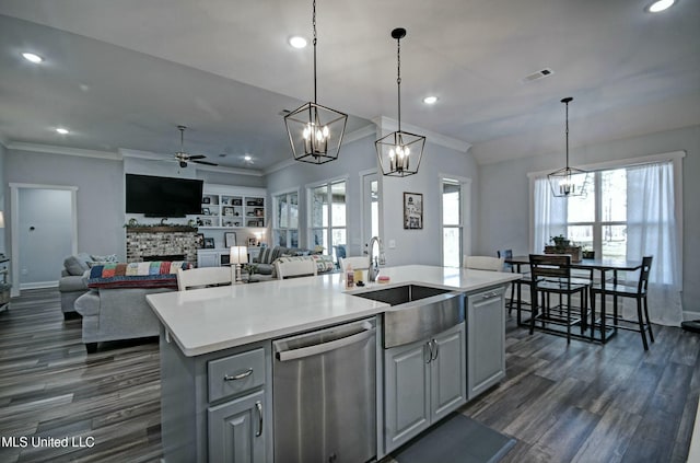 kitchen with ceiling fan with notable chandelier, a sink, a stone fireplace, a healthy amount of sunlight, and dishwasher