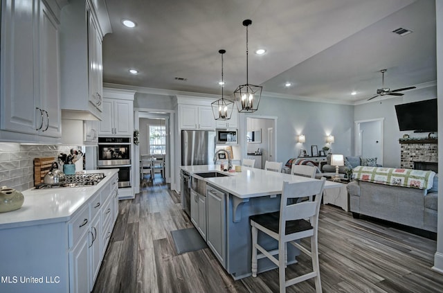 kitchen with a sink, stainless steel appliances, light countertops, decorative backsplash, and ceiling fan