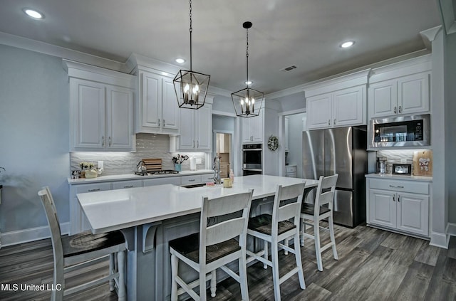 kitchen with light countertops, ornamental molding, stainless steel appliances, white cabinetry, and a sink