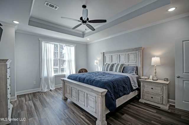 bedroom with visible vents, baseboards, ornamental molding, a raised ceiling, and dark wood-style flooring