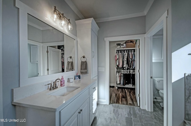 full bath with a walk in closet, baseboards, toilet, ornamental molding, and vanity