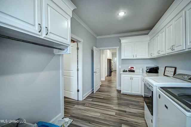 laundry area featuring independent washer and dryer, cabinet space, crown molding, baseboards, and dark wood-style flooring