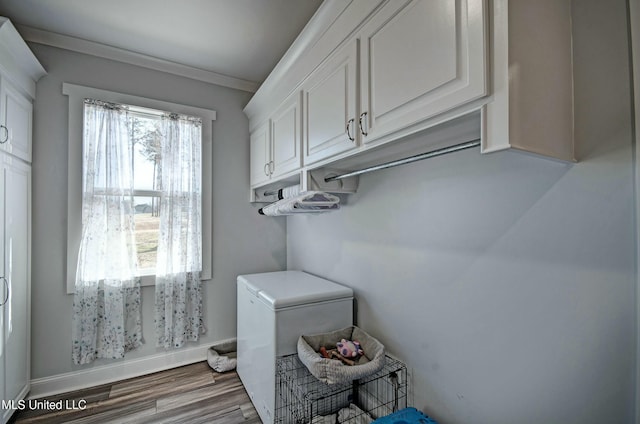 laundry room featuring ornamental molding, baseboards, and wood finished floors