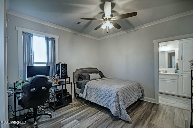 bedroom with a sink, crown molding, baseboards, and wood finished floors