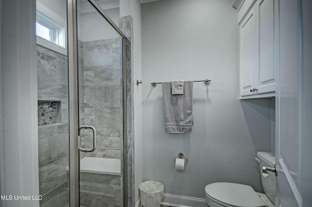 bathroom featuring a stall shower, toilet, and baseboards