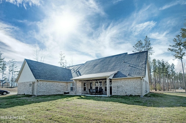 back of property with a yard, a patio area, and brick siding