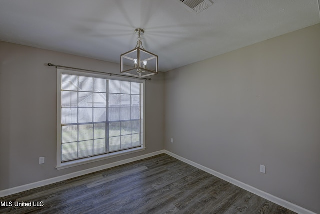 empty room with a wealth of natural light, an inviting chandelier, visible vents, and dark wood-style flooring