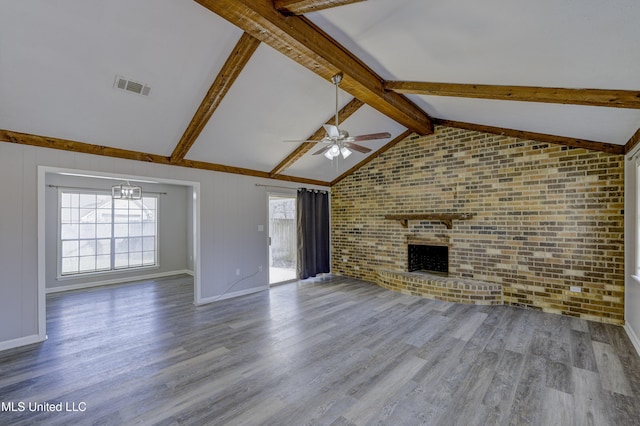 unfurnished living room featuring visible vents, lofted ceiling with beams, ceiling fan with notable chandelier, and brick wall