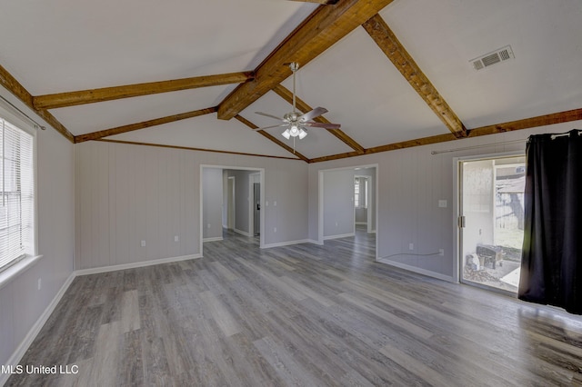 unfurnished living room with a ceiling fan, baseboards, visible vents, wood finished floors, and lofted ceiling with beams