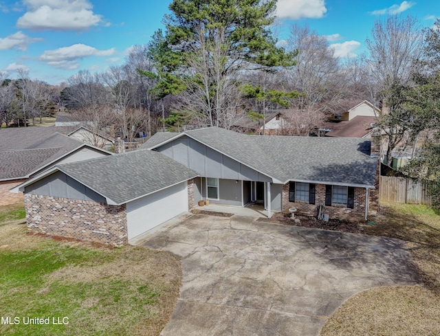 view of front of house with roof with shingles, fence, an attached garage, brick siding, and concrete driveway