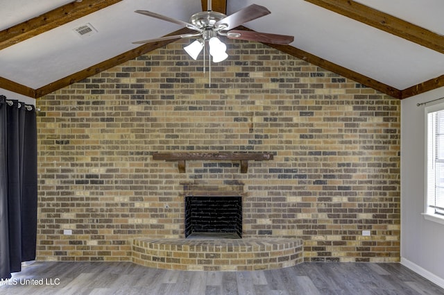 unfurnished living room featuring visible vents, a fireplace, a ceiling fan, brick wall, and vaulted ceiling with beams