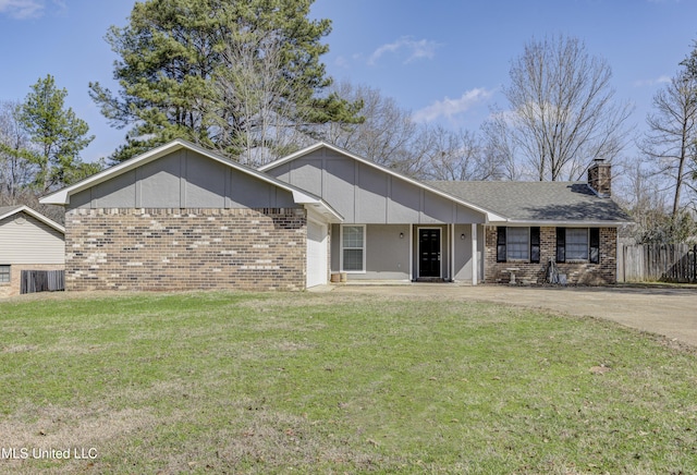 ranch-style home featuring a chimney, brick siding, a front lawn, and fence