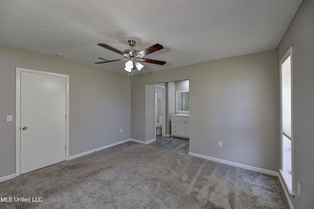 unfurnished bedroom with carpet flooring, a ceiling fan, ensuite bathroom, baseboards, and visible vents