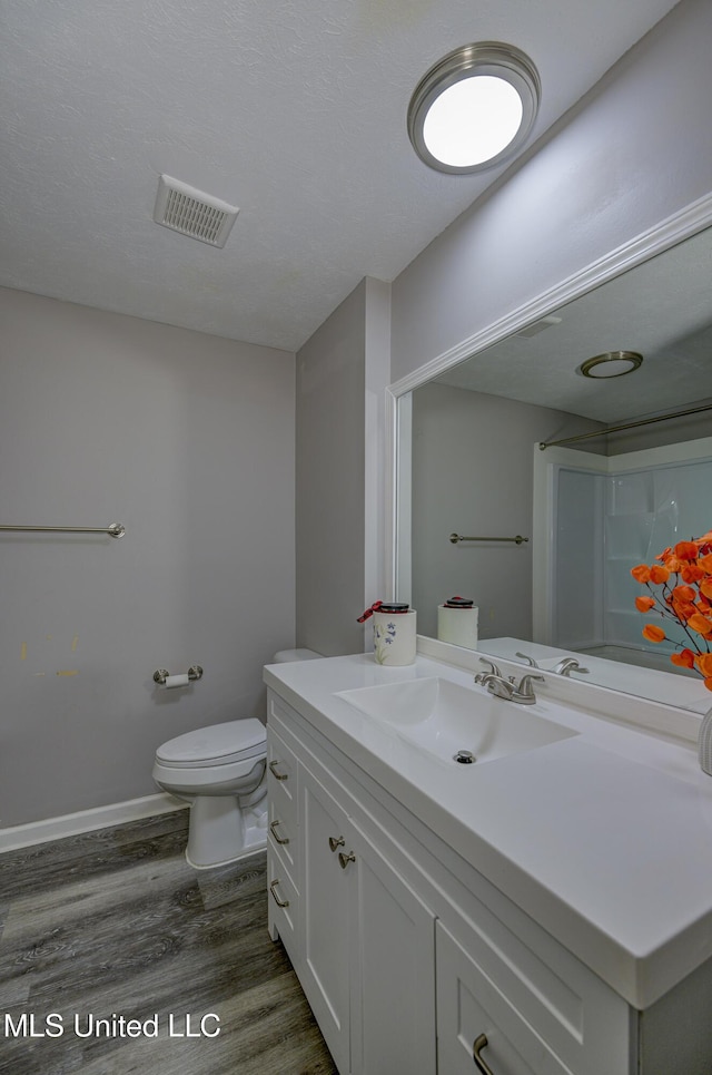bathroom with toilet, baseboards, visible vents, vanity, and wood finished floors