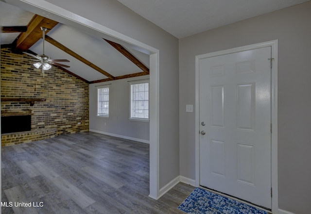 entrance foyer featuring wood finished floors, a brick fireplace, vaulted ceiling with beams, baseboards, and ceiling fan