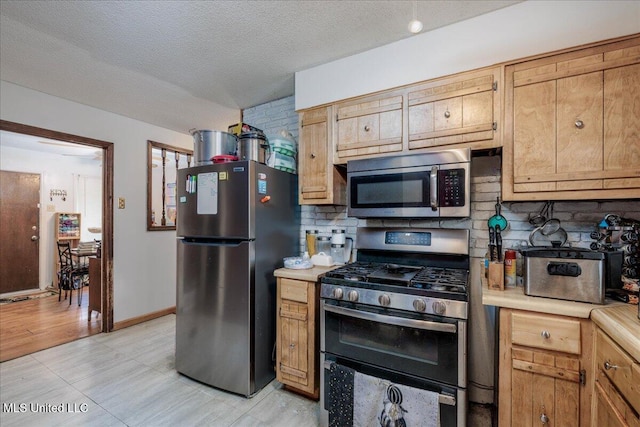 2880 Briarwood Dr, Horn Lake, MS 38637 - kitchen with appliances with stainless steel finishes, light countertops, decorative backsplash, a textured ceiling, and light tile patterned flooring
