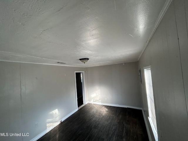 spare room featuring hardwood / wood-style floors, a textured ceiling, vaulted ceiling, ornamental molding, and wooden walls