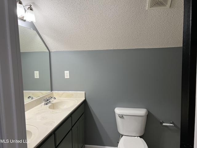 bathroom featuring vanity, a textured ceiling, vaulted ceiling, and toilet