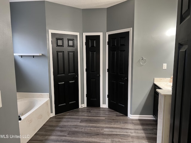 bathroom with vanity, hardwood / wood-style flooring, a tub, and a textured ceiling