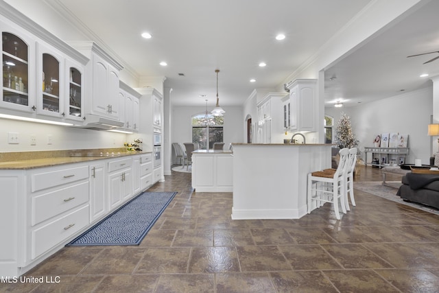 kitchen featuring black electric stovetop, white oven, ceiling fan with notable chandelier, pendant lighting, and white cabinets