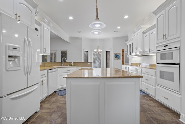 kitchen with kitchen peninsula, white appliances, decorative light fixtures, a center island, and white cabinetry