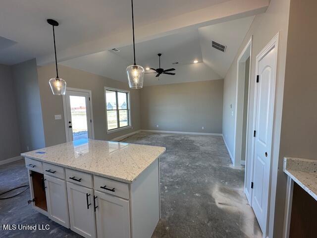 kitchen with white cabinets, vaulted ceiling, light stone countertops, and pendant lighting