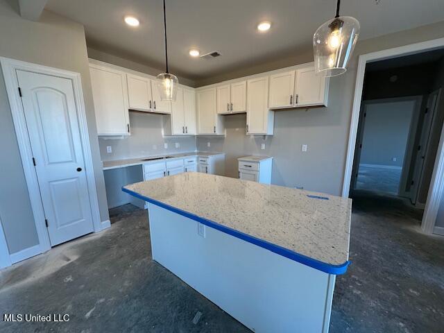 kitchen with white cabinetry, a center island, hanging light fixtures, and light stone counters