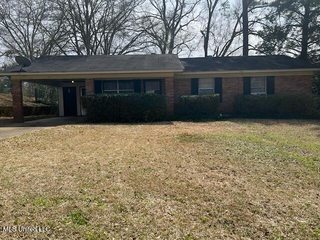 ranch-style home featuring brick siding, an attached carport, and a front yard