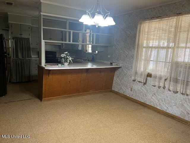 kitchen with baseboards, freestanding refrigerator, brown cabinets, wallpapered walls, and crown molding