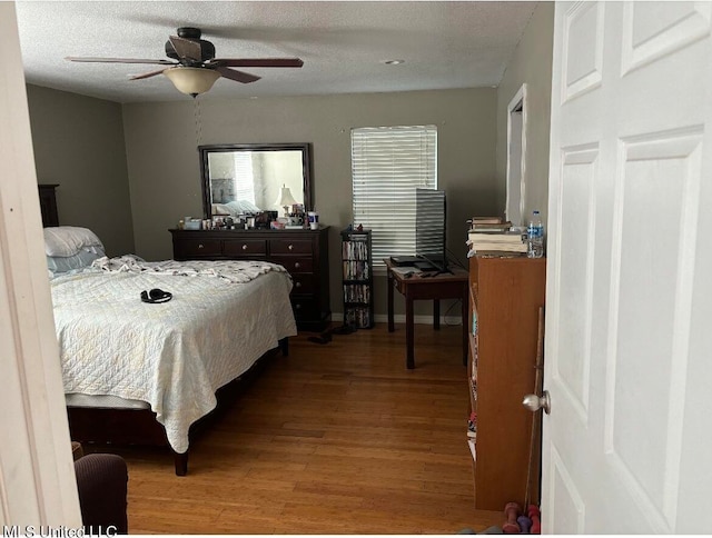 bedroom featuring hardwood / wood-style floors, a textured ceiling, and ceiling fan