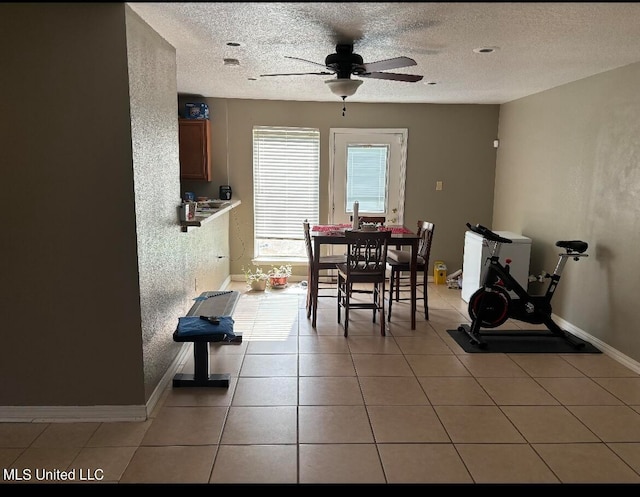 tiled dining space with a textured ceiling and ceiling fan