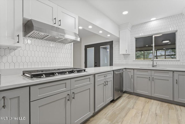 175 Saint Charles Ave, Biloxi, MS 39530 - kitchen with under cabinet range hood, stainless steel appliances, gray cabinets, light countertops, and backsplash