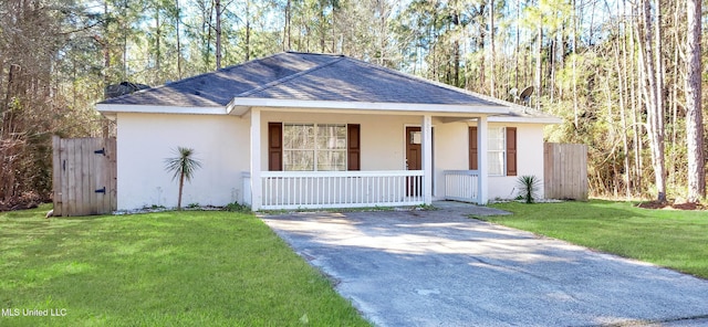 view of front facade with stucco siding, roof with shingles, a porch, and a front lawn