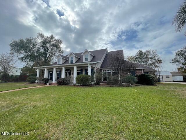 cape cod-style house featuring a front lawn and covered porch