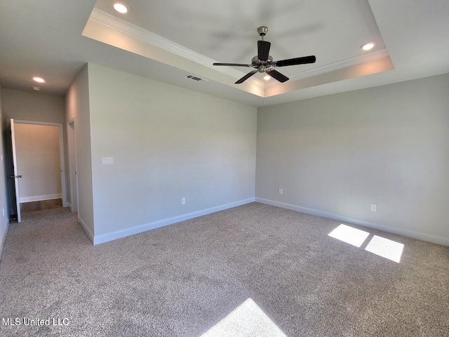 carpeted spare room with crown molding, ceiling fan, and a raised ceiling