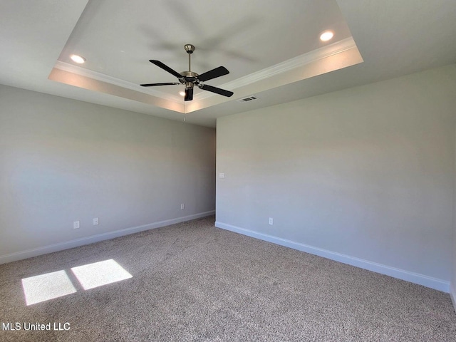 carpeted spare room with a tray ceiling, ornamental molding, and ceiling fan