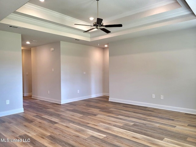 unfurnished room featuring a raised ceiling, crown molding, hardwood / wood-style floors, and ceiling fan