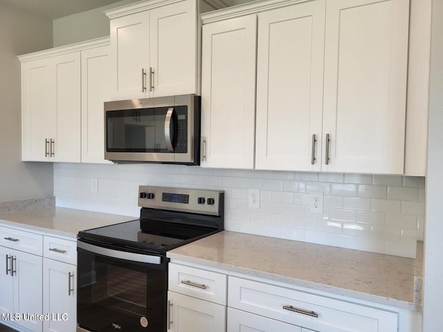 kitchen featuring light stone counters, backsplash, white cabinets, and appliances with stainless steel finishes