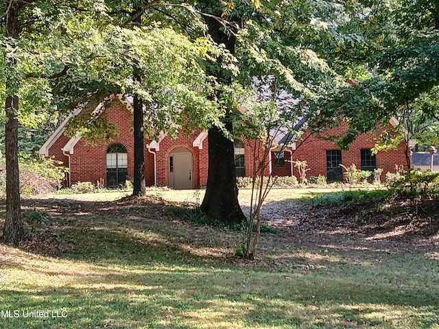 view of front facade with brick siding and a front lawn