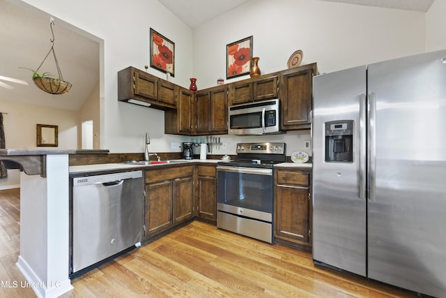 14174 Spruce Ct, Gulfport, MS 39503 - kitchen with appliances with stainless steel finishes, a sink, light wood-style floors, vaulted ceiling, and dark brown cabinetry