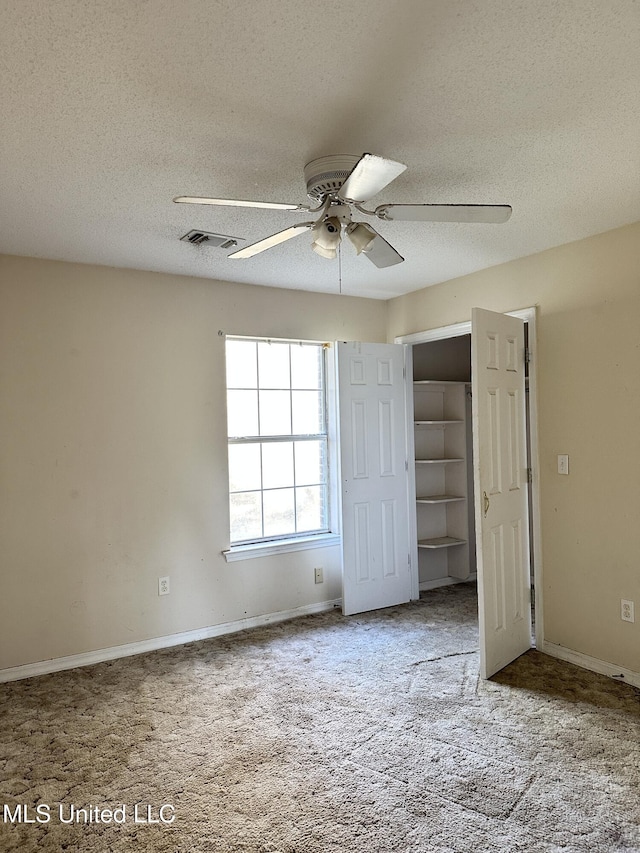 unfurnished bedroom featuring carpet flooring, a textured ceiling, a closet, and ceiling fan