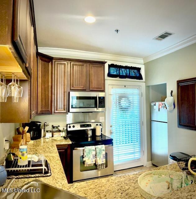 kitchen featuring crown molding, stainless steel appliances, and light stone counters