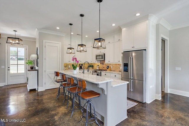 kitchen featuring appliances with stainless steel finishes, white cabinetry, a kitchen island with sink, and hanging light fixtures