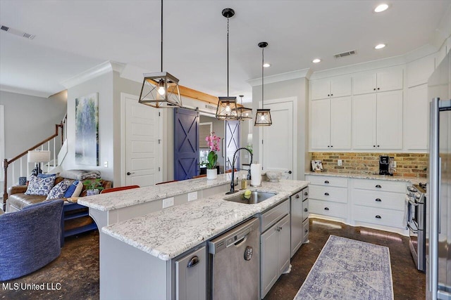 kitchen with a barn door, stainless steel appliances, a center island with sink, and sink